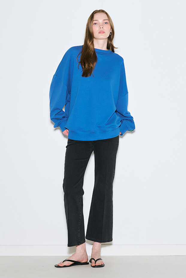 سترة رياضية كبيرة الحجم مزينة بملصق باللون الأزرق