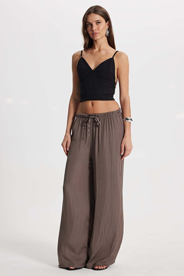 Women's relaxed fit wide leg trousers in light brown with drawstring waist and elasticated hems.