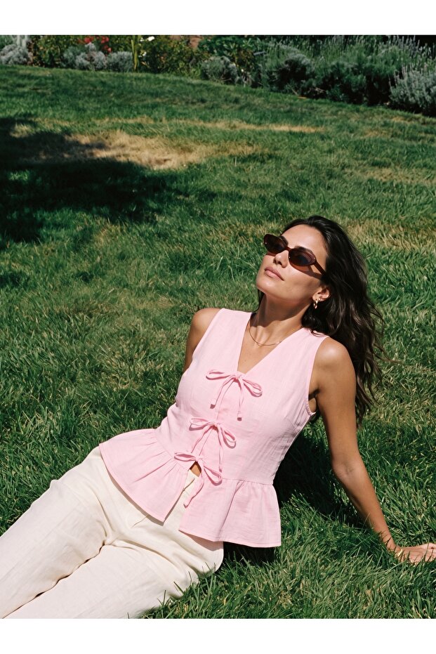Pink Cotton Muslin V-Neck Peplum Form-Fitting Sleeveless Blouse with Front Bow Tie Detail