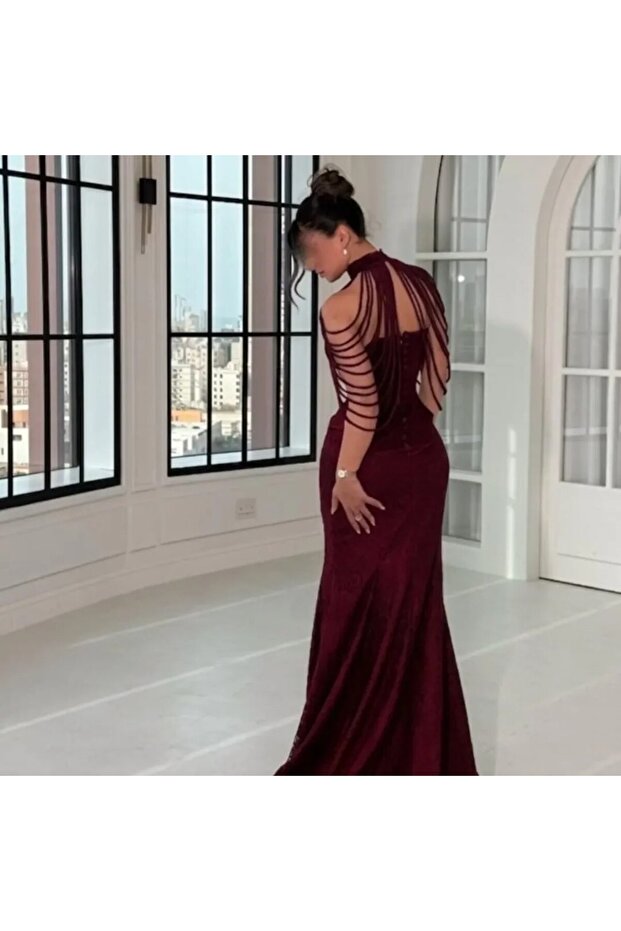 فستان سهرة عنابي طويل بتصميم ضيق وأشرطة زينة حول الأكتاف.