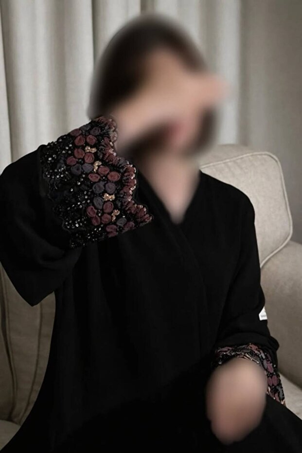 Elena's luxurious black abaya features practical buttons and shimmering embroidery – an elegant design suitable for both special occasions and everyday wear.