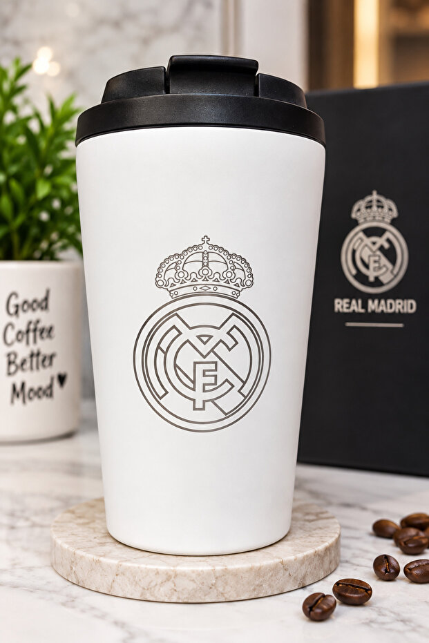 كوب حراري أنيق باللون الأبيض مع غطاء أسود عملي وشعار ريال مدريد، مناسب للمشروبات الساخنة والباردة والاستخدام اليومي في المنزل أو العمل أو أثناء التنقل.