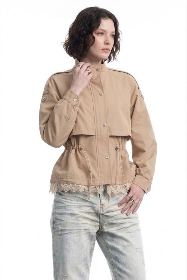 Women's beige trench coat with ruched waist, lace detail, and short length.
