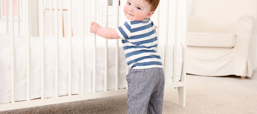 ребенок пытается идти держась за стену