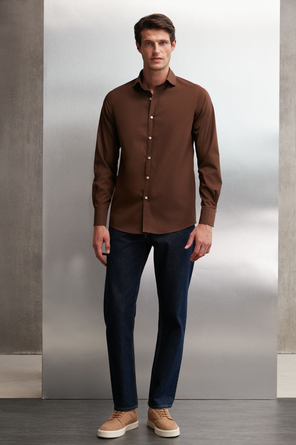 Premium Photo | A man in a grey shirt and green pants stands on a brown  background.