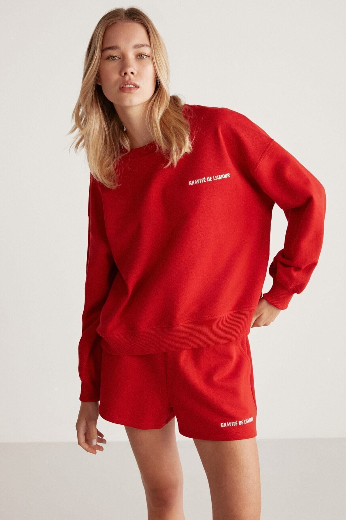 jennifer le sweat shirt rouge avec les détails de la pression sur le vélo de la femme