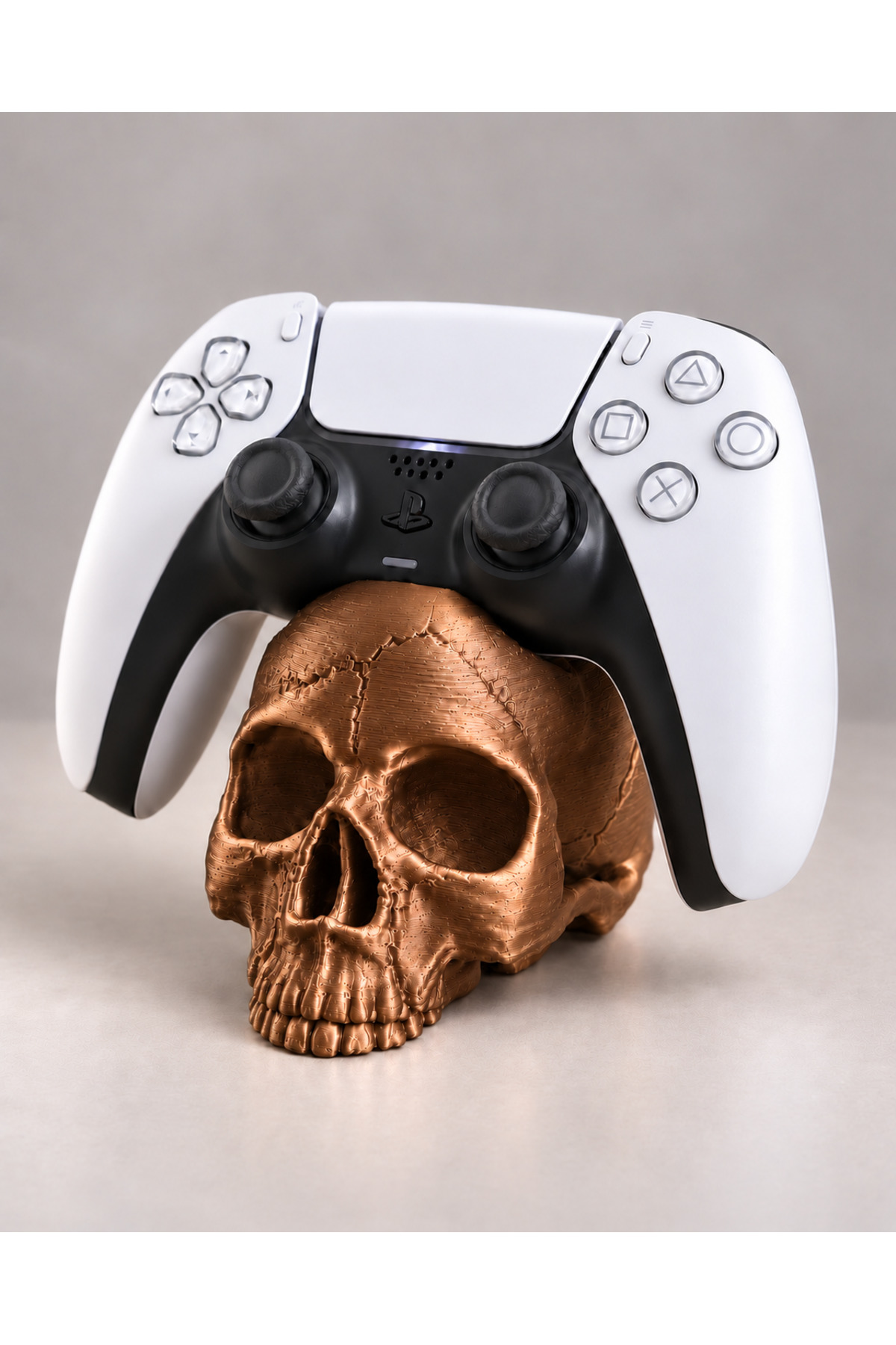 Kurukafa Ps5 Gamepad Stand - Metalik Bronz, PS5 kolunu kafatası üzerinde taşıyan masaüstü görünümü.